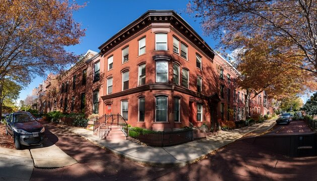 corner brownstone townhouse with central stoop and tree shadows