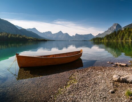 boat on the shore of a lake rocky shore mountains in the distance landscape photography