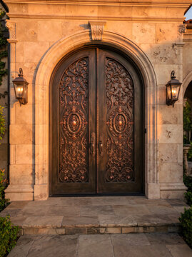 Stately arched heavy wooden double door framed by rustic stone walls and outdoor lamps with entrance, architecture