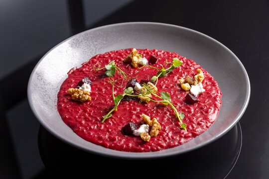 Beetroot risotto served with walnuts goat cheese and microgreens