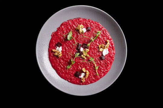 Vibrant red beetroot risotto top view with walnuts and cheese on grey plate