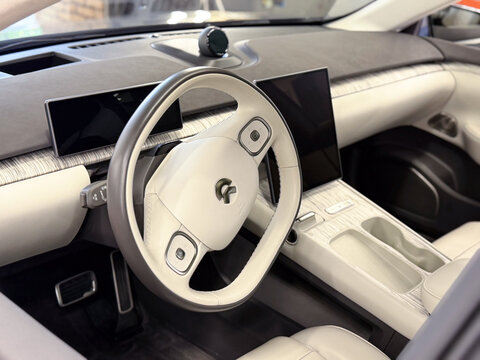 Modern interior design of NIO premium electric car with white leather steering wheel, digital dashboard screen and multimedia display. Luxury smart EV automobile cockpit and dashboard view. Tech car. 