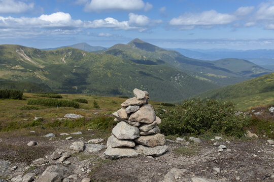 stone tower atop a mountain, set against a beautiful sky and the Carpathian landscape, including Hoverla, Ukraine's highest peak. A concept of equilibrium, balance, and stability,