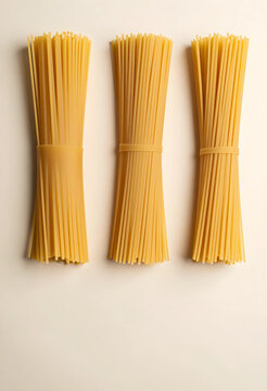 Italian food and cooking ingredients, three bundles of raw spaghetti pasta on a light background, top view