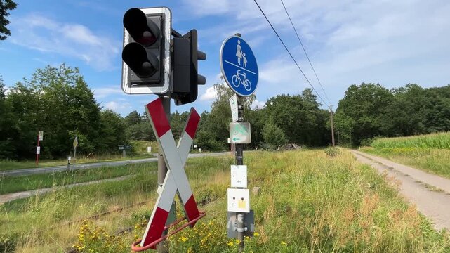 Railway crossing with warning signal, crossbuck and shared pedestrian bicycle path beside rural road
