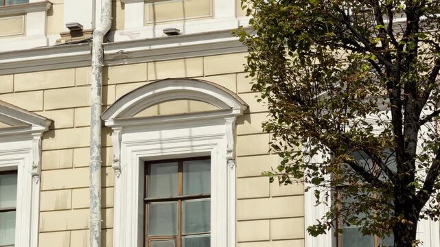 A historic yellow building stands gracefully along a sunny street in Saint Petersburg. Its detailed facade inspires a peaceful feeling of quiet admiration.
