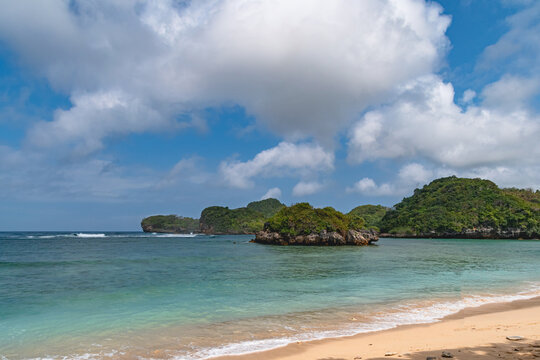 Scenic Gatra Beach in Malang, East Java, Indonesia, featuring clean sandy shores, calm blue seawater and beautiful small islands surrounded by pristine tropical coastal scenery