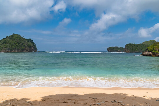 Scenic Gatra Beach in Malang, East Java, Indonesia, featuring clean sandy shores, calm blue seawater and beautiful small islands surrounded by pristine tropical coastal scenery