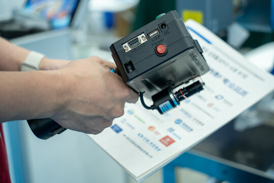 Person operating a handheld coding printer in a workshop