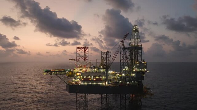 Aerial top view of offshore jack up rig and offshore platform during sunset for oil and gas exploration and production. 