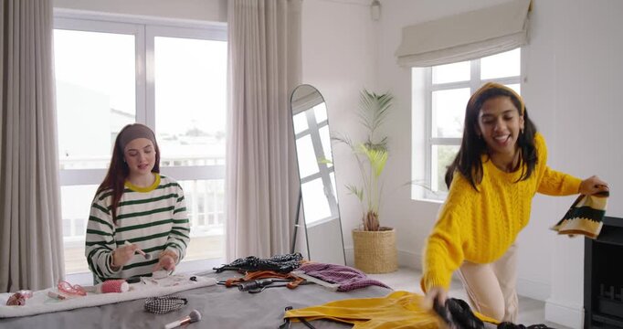 Diverse women friends bringing yellow dress, sorting outfits on bed, doing makeup and styling looks