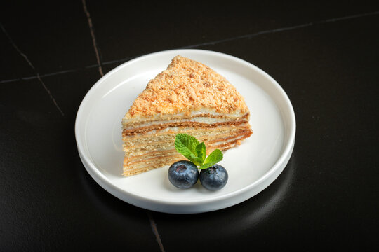 Medovik. Honey cake made from honey cakes with whipped sour cream, decorated with berries, pomegranate and flowers