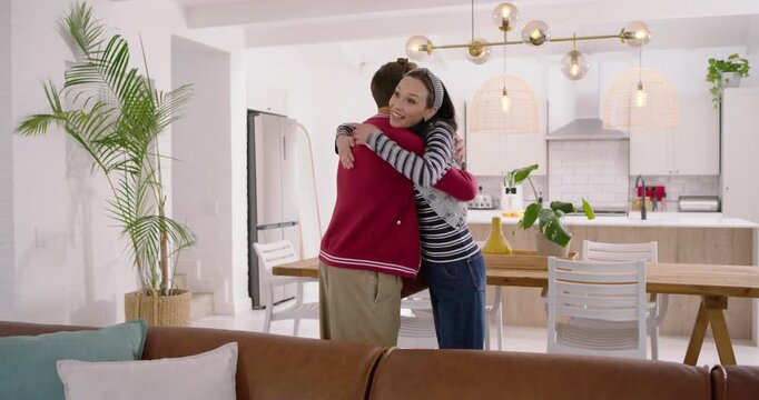 Couple entering living room pulling suitcase, hugging, sitting on sofa and exploring space