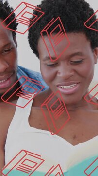 Animation of book icons over african american couple reading