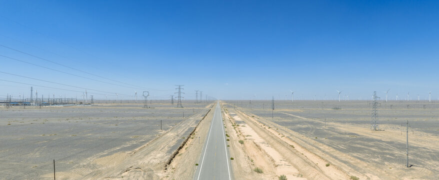 Aerial View of Straight Desert Highway with Power Lines and Wind Turbines in Gobi Desert