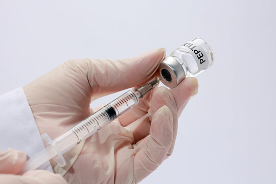 Medical professional holding syringe and vial preparing peptide therapy with focused serious expression in clinic setting