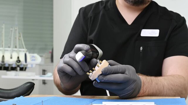 A dental technician uses a 3D optical scanner to digitize a physical dental model, transferring precise three-dimensional data to a computer for digital dental design and CAD CAM manufacturing no face