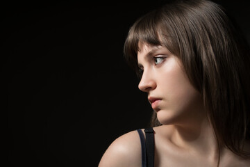 Fototapeta premium Portrait of a beautiful young teenage girl posing against a dark background