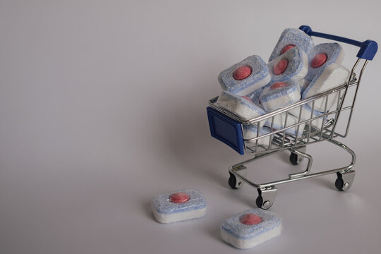 Organized laundry: stack of bright dishwasher tablets in a wire shopping trolley