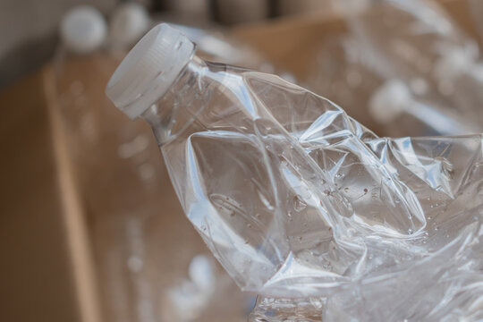 crushed plastic water bottle saving space in cardboard box of materials collected for recycling