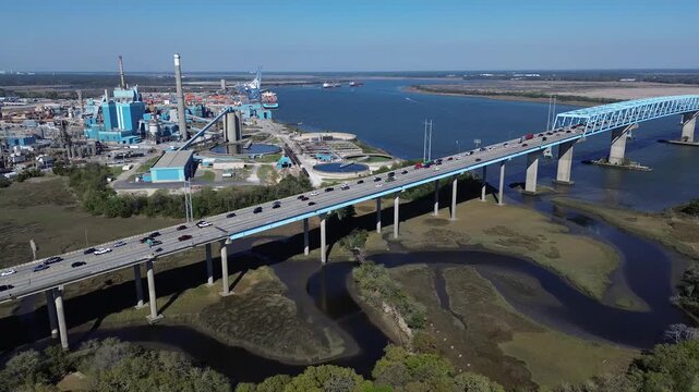 Winding saltwater creeks flow beneath Interstate 526 viaducts toward South Carolina Cooper River channels. Elevated concrete piers carry active automotive traffic, North Charleston