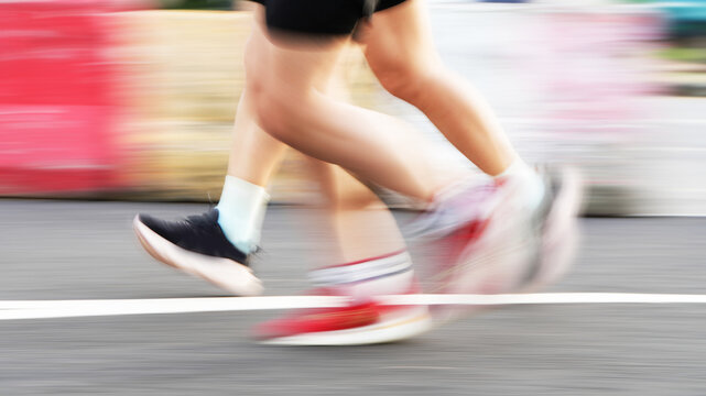 Close-up view of runners&rsquo; legs captured with motion blur, conveying speed, movement, energy, and competitive athletic performance
