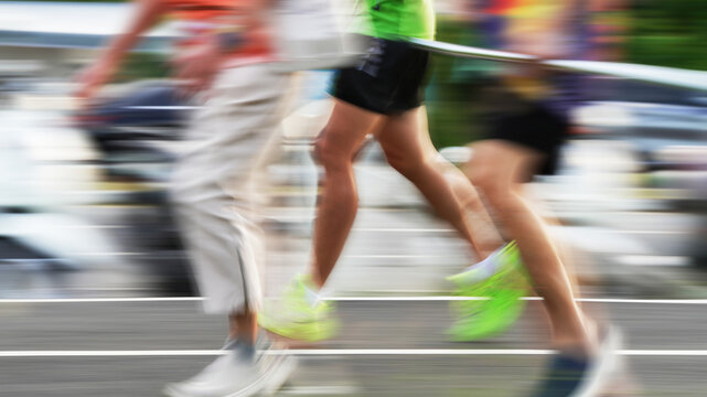 Motion-blurred runners competing in a road race, creating a dynamic sense of speed, movement, energy, and athletic performance