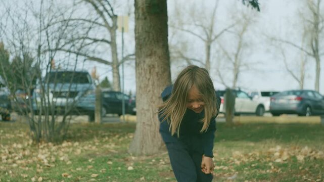 Boy reaching and catching in an autumn park with fallen leaves
