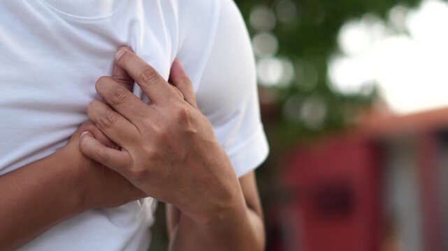 Men have chest pain. hand hold chest with heart attack symptoms, caused by heart disease, leak, dilatation, enlarged coronary heart, press on the chest with a painful expression.	