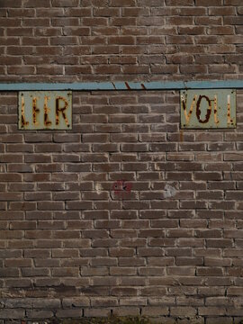 Brick wall with two signs on it, one of which says "Ler Vol"
