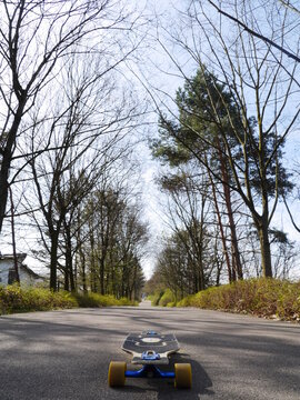 Skateboard is laying on the road in front of a forest