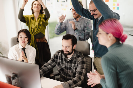 Group of business professionals celebrating teamwork success in a modern office setting during a project review