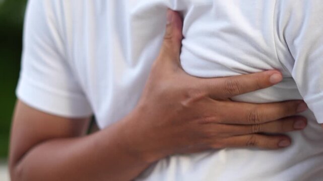 Men have chest pain. hand hold chest with heart attack symptoms, caused by heart disease, leak, dilatation, enlarged coronary heart, press on the chest with a painful expression.	
