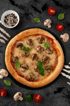 Halloween mushroom pizza with basil, cheese and spooky skeleton decoration on a dark background, creative food concept for seasonal menus. Funny food idea. Top view.