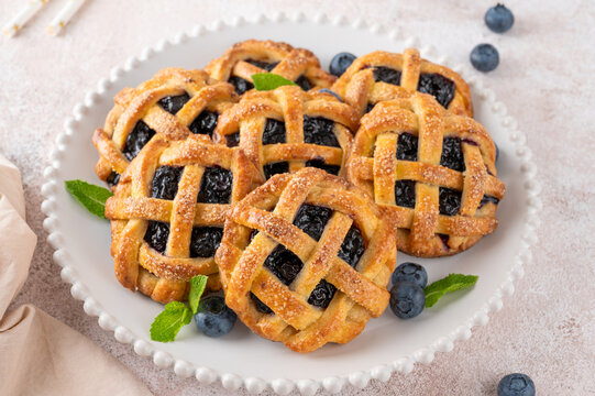 Homemade blueberry hand pies or mini tarts with milk on a concrete background.