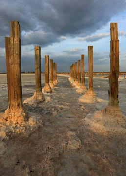 Wooden posts in a salt lake surface with dramatic clouds overhead