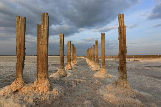 Wooden posts in a salt lake surface with dramatic clouds overhead