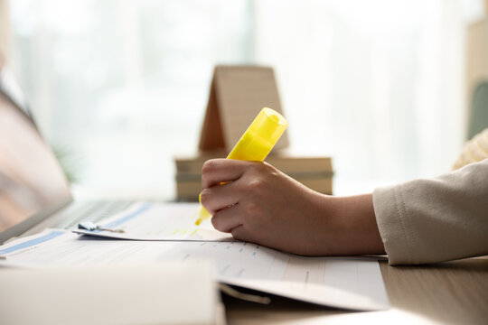 Close up hand highlighting text on business strategy document with yellow marker, concept of data analysis, paperwork review and exam preparation.