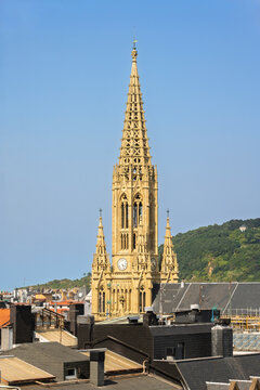 Gothic bell tower of Good Shepherd Cathedral rising above rooftops, viewed from San Bartolome viewpoint in San Sebastian, Spain.