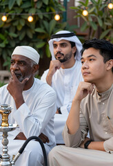 Obraz premium Multigenerational arab men in traditional clothing, cultural diversity and community gathering, thoughtful expressions outdoors