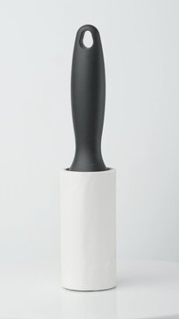 White sticky lint roller with handle rotating isolated on white background.