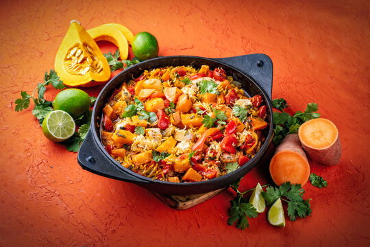 Slow cooked casserole dish  healthy yummy spicy Italian one-pan role stew vegetable pumpkin, sweet potato, chicken and rice served as close-up in a design casserole