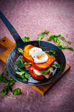 Traditional artisan croque monsieur chevre - hot brioche bread sandwich with prosciutto, arugula and goat cheese roasted in butter served as close-up in a rustic frying pan
