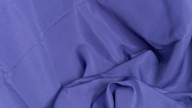 visual presents a magnificent top down perspective of a soft blue purple cloth featuring dramatic waves and elegant gathered folds on the right side. The refined material beautifully
