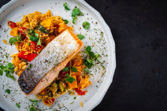 Fried salmon fish fillet with pumpkin and sweet potato rosti gratin served as top view on a design plate