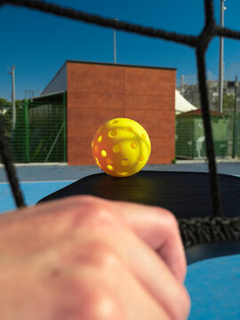 Pickleball ball flying over net during game