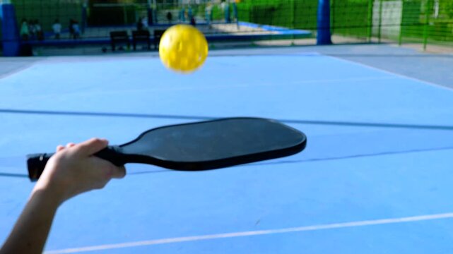 Woman bouncing a yellow pickleball on a paddle