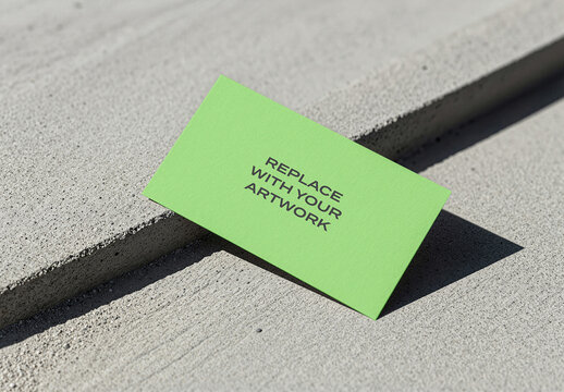 Business card mockup on a concrete surface in an outdoor urban environment, minimalist stationery presentation with natural light shadow, template for print design text placeholder artwork