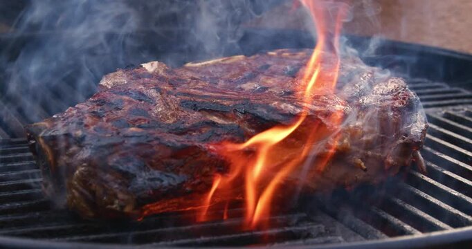 Barbecue dry aged entrecote roast beef steaks grilled as close-up on a charcoal grill with fire and smoke