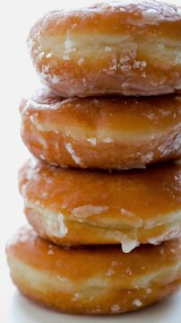 Slow motion vertical video of stacked glazed donuts rotating close up
